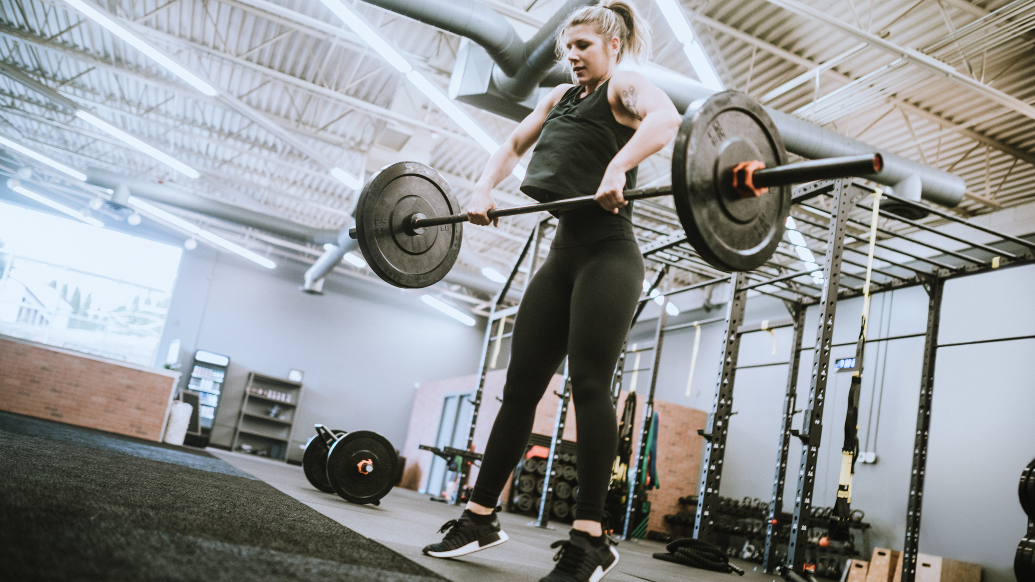 A woman in triple extension lifting a barbell midway through the high pull