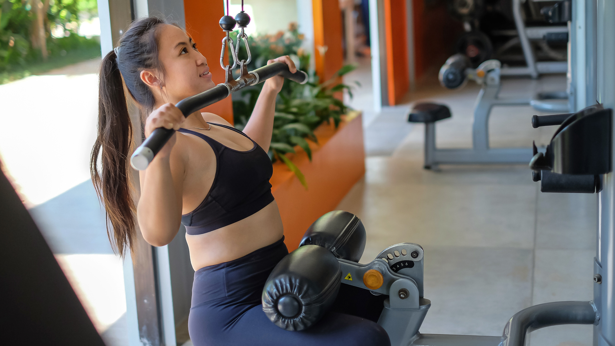 Woman exercises on the lat pull-down weights machine