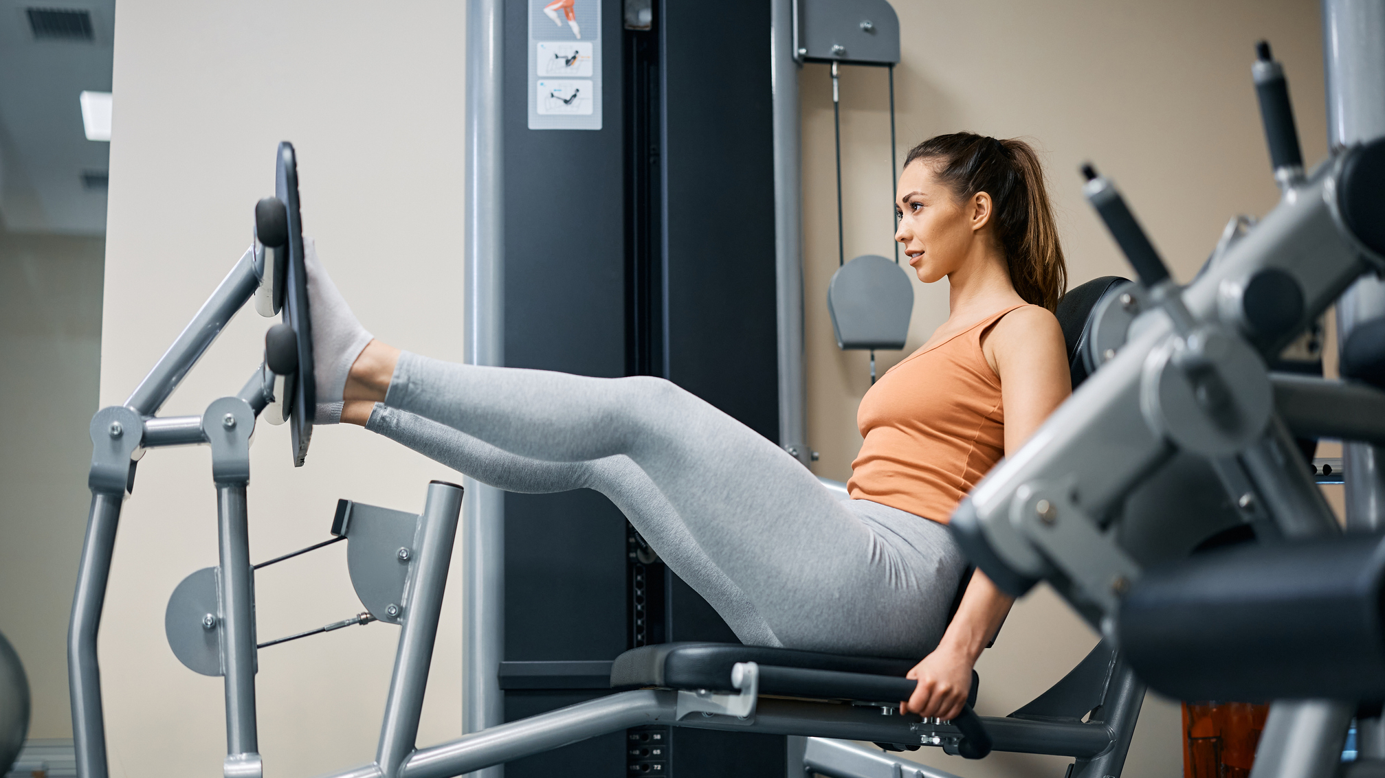 Woman exercises on the leg press machine in a gym